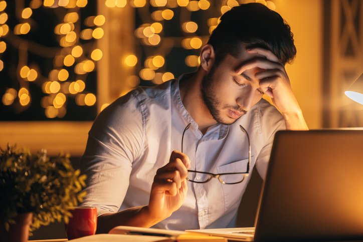 A fatigued young man is working late on a project.