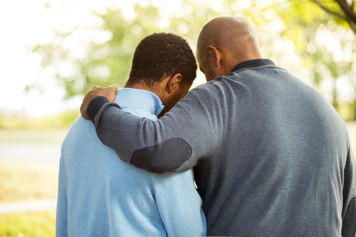 A father puts his hand around his insecure son's shoulders.