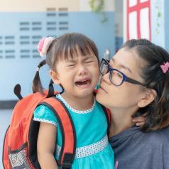 Young child crying with mom at school drop-off
