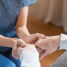 Assisting senior people. Close up of female caregiver holding elderly woman's hands indoors